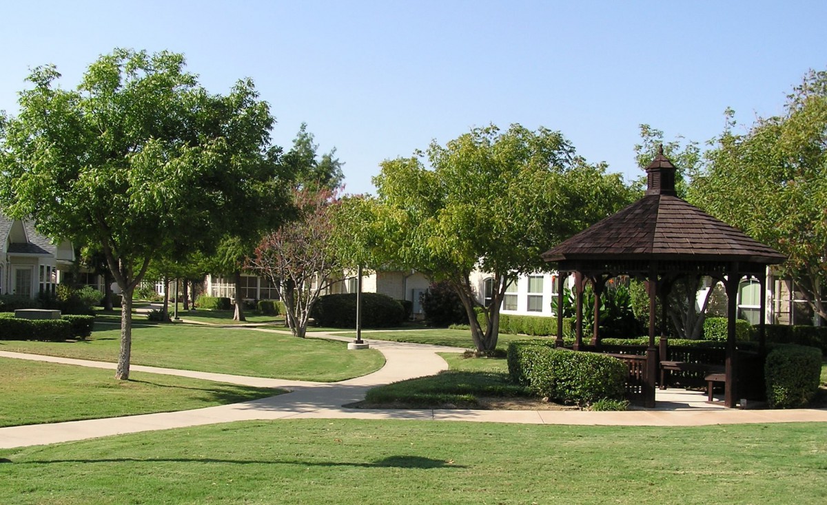 A peaceful park scene with a gazebo, surrounded by trees and well-maintained pathways.