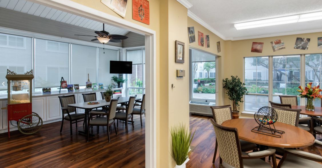 A cozy dining area with wooden floors, elegant furniture, and large windows providing natural light.