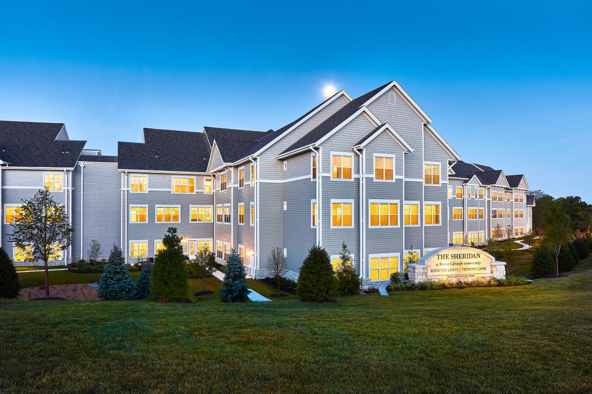 A well-lit hotel building at dusk with a maintained lawn.