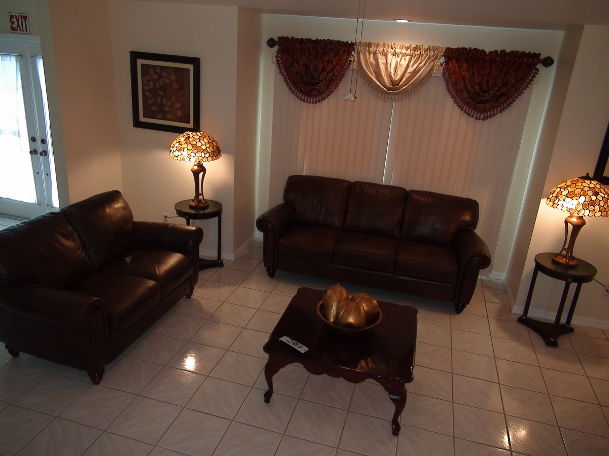 A stylish living room with brown leather sofas, a coffee table, and elegant curtains.