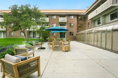 A spacious outdoor patio area with seating and an umbrella in an apartment courtyard.