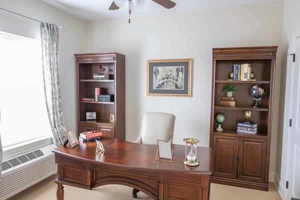 A well-organized home office with wooden furniture, including a desk and bookshelves.