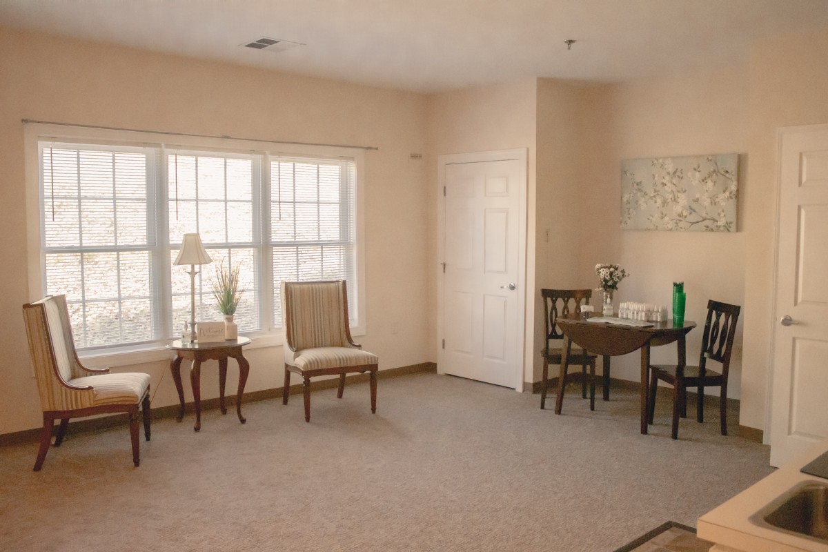 A cozy room with chairs, a table, and a large window allowing natural light.