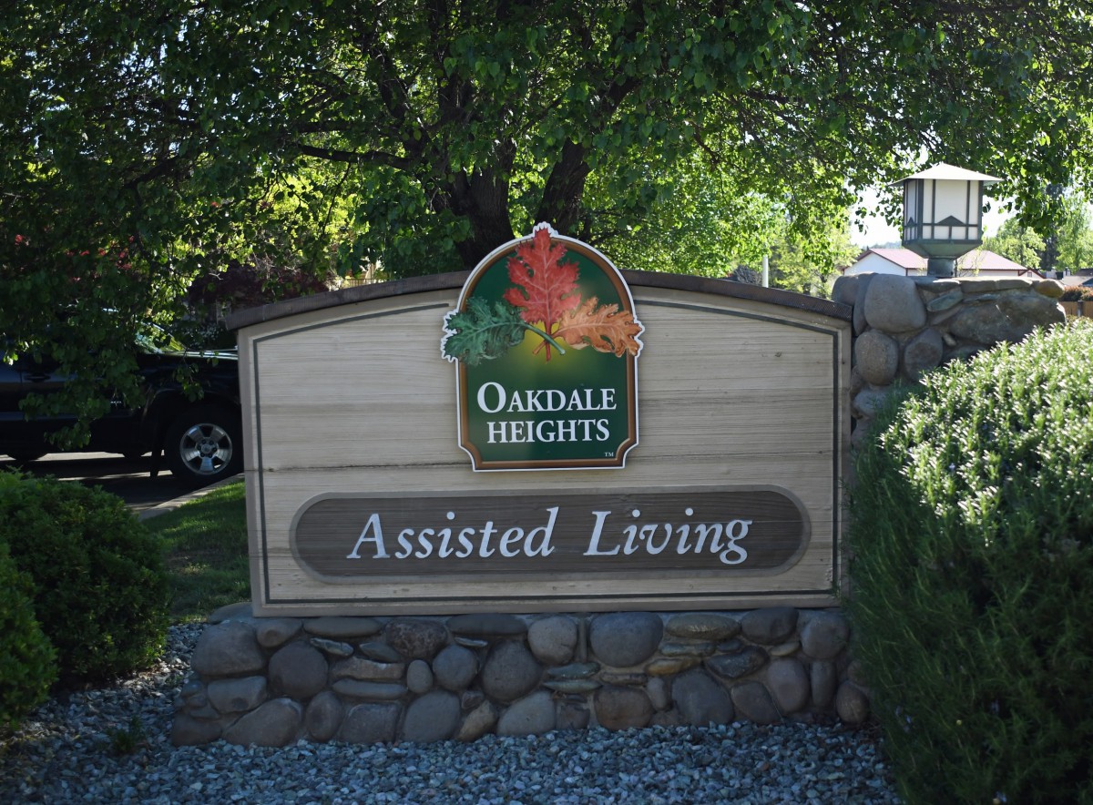 Sign for Oakdale Heights Assisted Living surrounded by trees and landscaping.