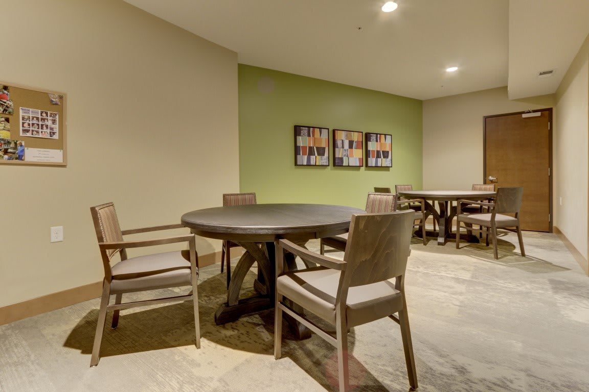 A modern room with a round table and chairs, featuring artwork on the wall.