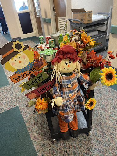 A cheerful scarecrow surrounded by vibrant autumn flowers and decorations, ready to celebrate the fall season.