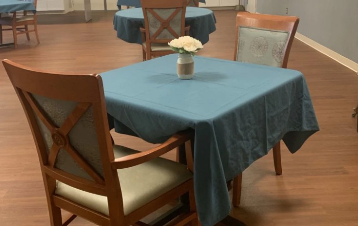 A dining table with a blue tablecloth and a flower vase in an interior setting.
