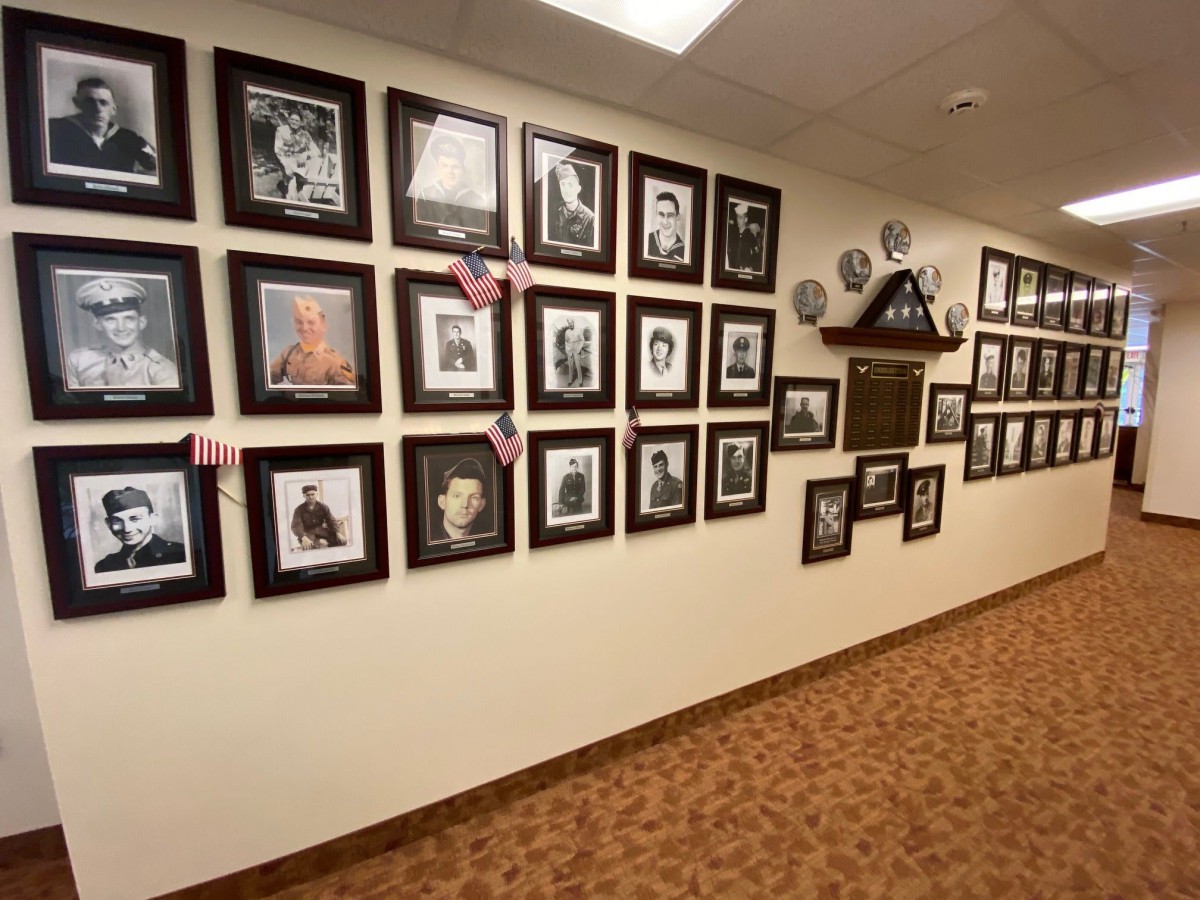 A hallway adorned with a series of framed portraits and photographs displayed on the wall.