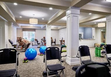 A well-equipped gym with exercise balls, chairs, and fitness machines in a spacious indoor setting.