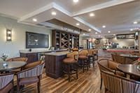 A stylish bar with seating and wine racks, featuring elegant interior design and wood flooring.