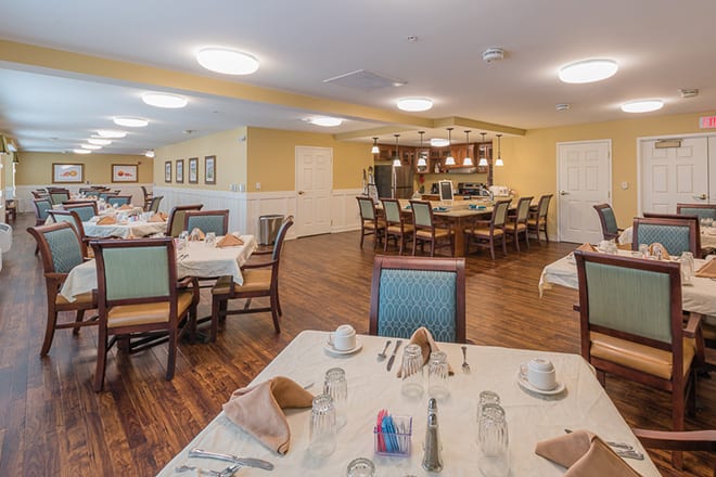 A cozy dining area featuring neatly arranged tables and chairs with warm lighting.