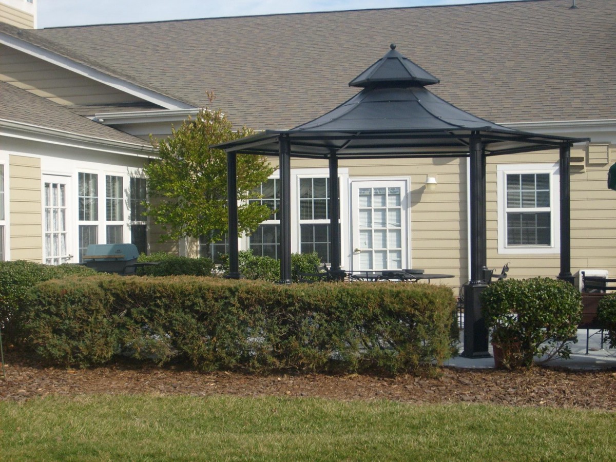 A well-maintained garden with a gazebo in front of a residential building.