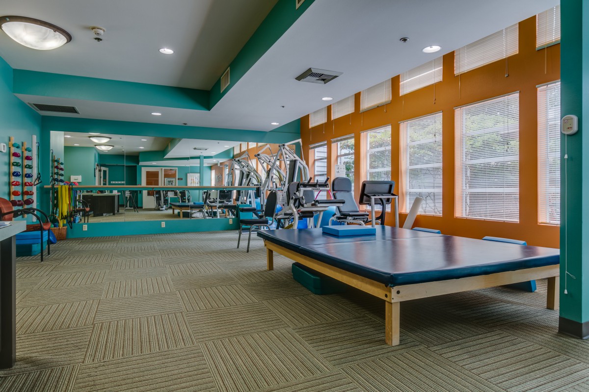A spacious gym with exercise equipment and large windows.