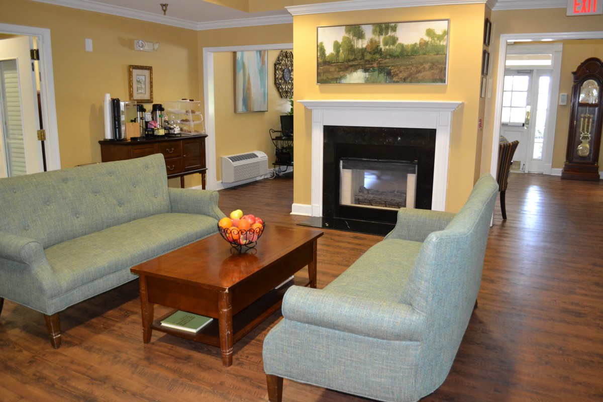 A cozy living room with sofas arranged around a fireplace and a wooden coffee table.