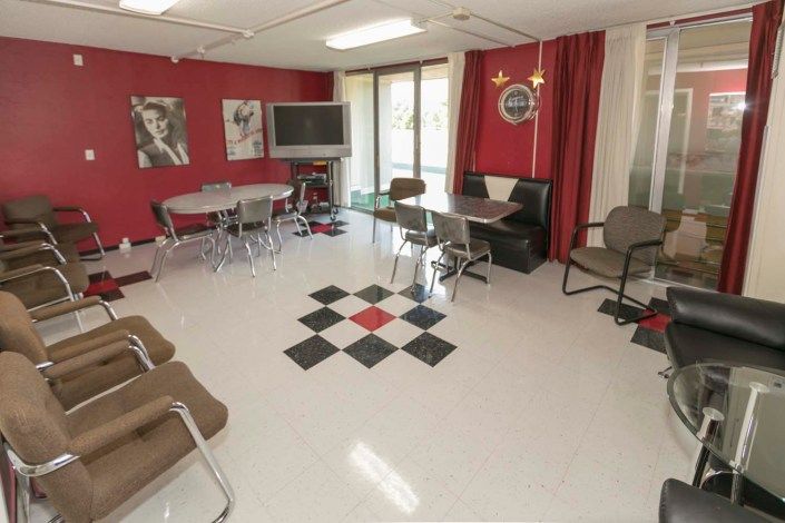 A retro-themed room with red walls, diner-style seating, and black and white floor tiles.