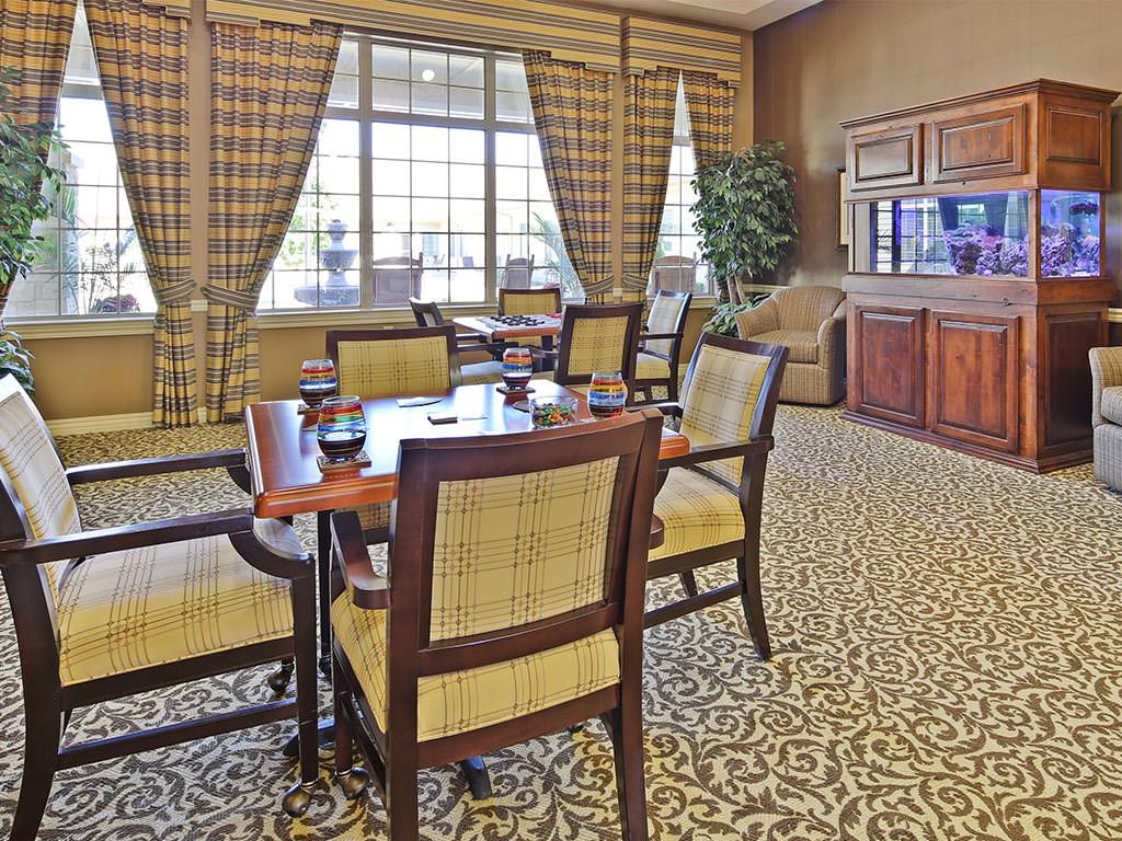 A well-furnished meeting room with a central table, chairs, and large windows with plaid curtains.