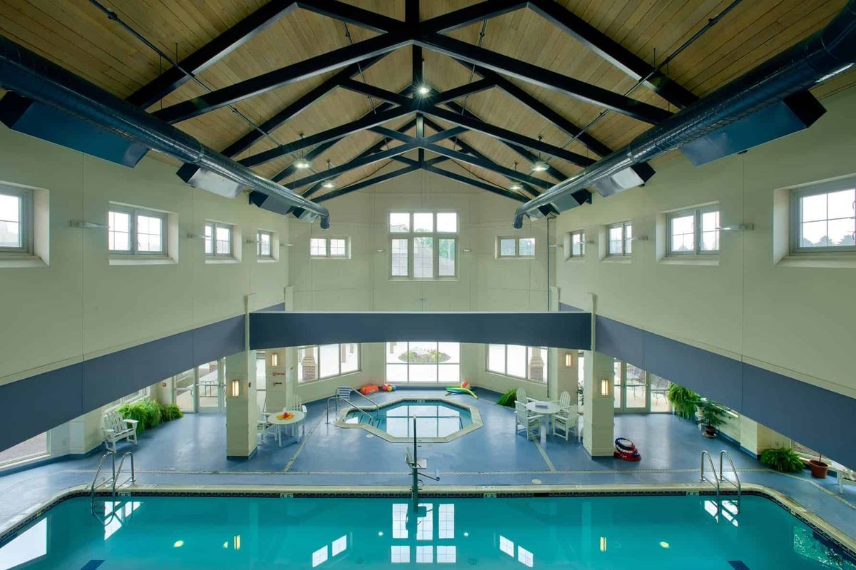 A spacious indoor swimming pool with a high ceiling and attached spa area.