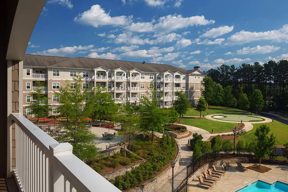 A scenic view of a residential apartment building surrounded by lush greenery and well-maintained pathways.