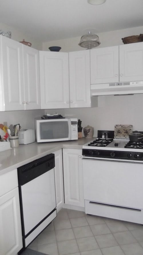 A modern kitchen with white cabinets and various appliances.