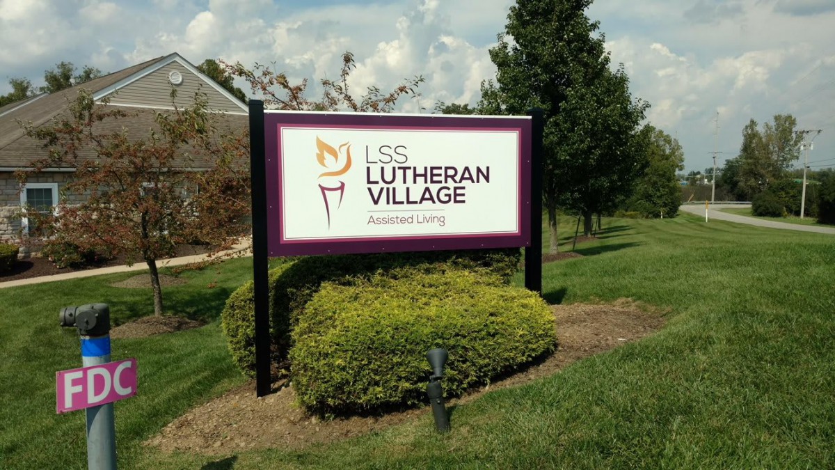 A sign for LSS Lutheran Village Assisted Living surrounded by greenery.