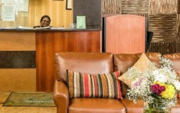 A cozy lobby area with a sofa adorned with colorful cushions and a reception desk in the background.