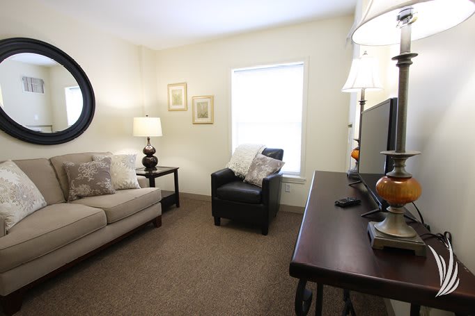 A cozy living room with a sofa, armchair, and decorative lamps.
