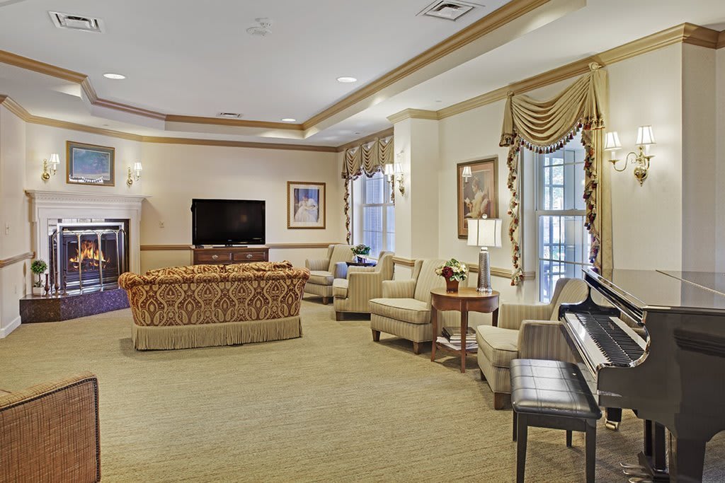 A spacious and elegantly designed living room featuring comfortable seating, a television, and a piano.