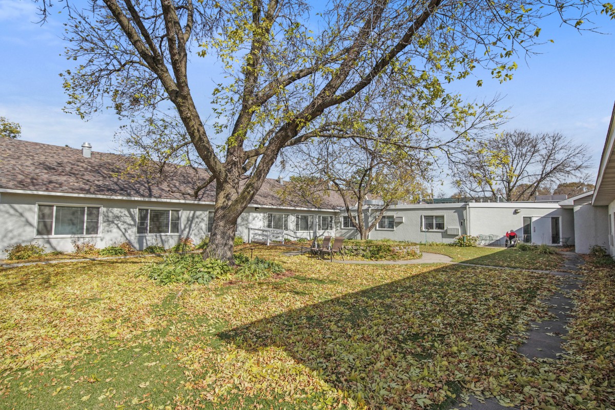 A single-story house surrounded by trees and fallen leaves on an autumn day.