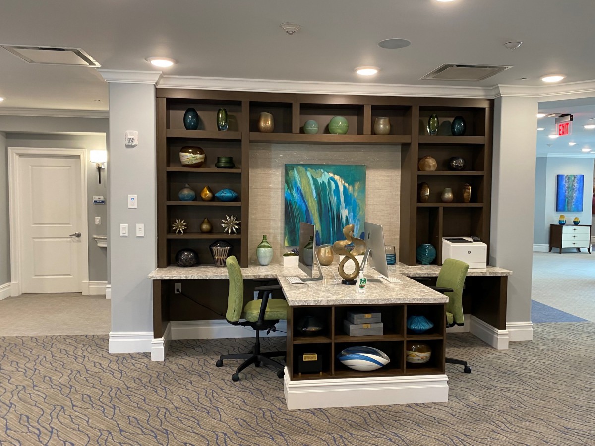 A modern office space with a desk, shelves, and decorative artwork.