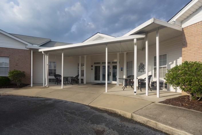 A covered entrance of a building with pillars and outdoor seating.