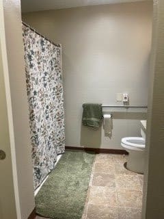 A bathroom with a floral shower curtain and green bath accessories.