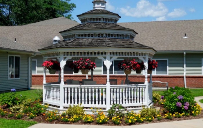 A picturesque gazebo surrounded by vibrant flowers in a garden setting.