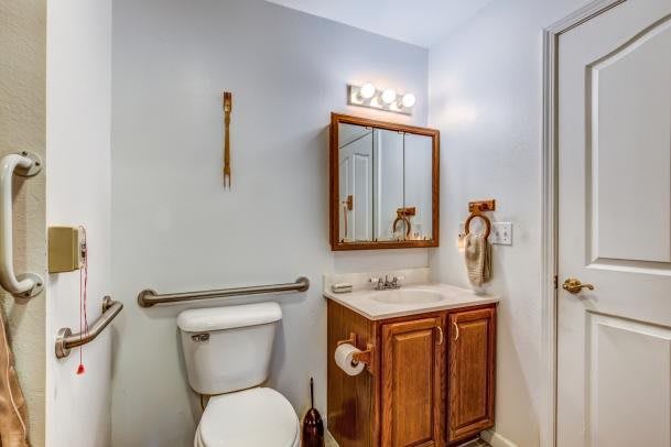 A small bathroom with a toilet, vanity, and mirror.