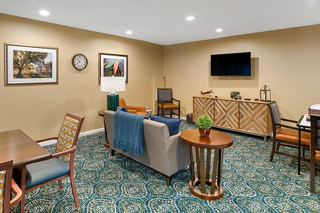 A cozy living room with a sofa, television, and patterned carpet.