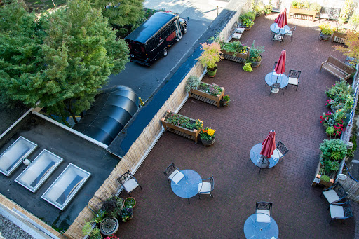 Aerial view of a cozy outdoor patio area with tables and plants, featuring a vehicle parked nearby.