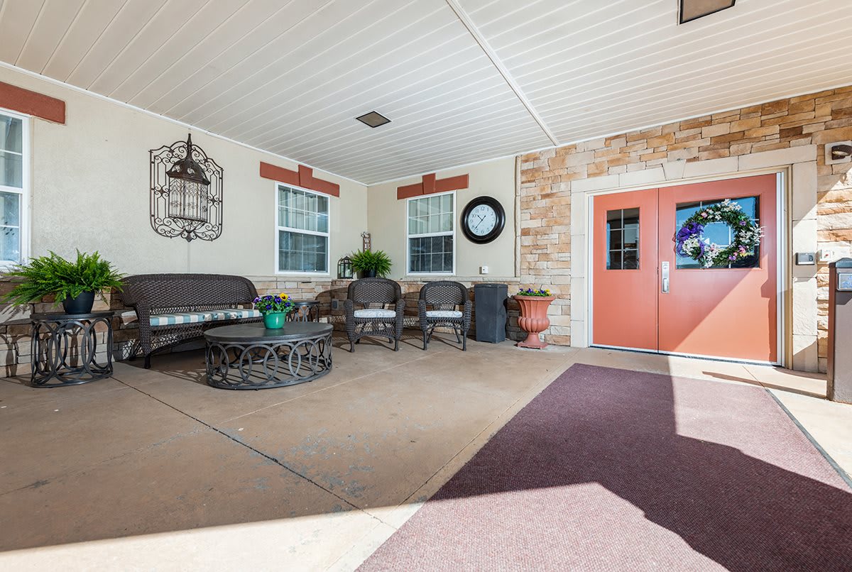 A cozy outdoor seating area with a couch, chairs, and decor next to a building entrance.