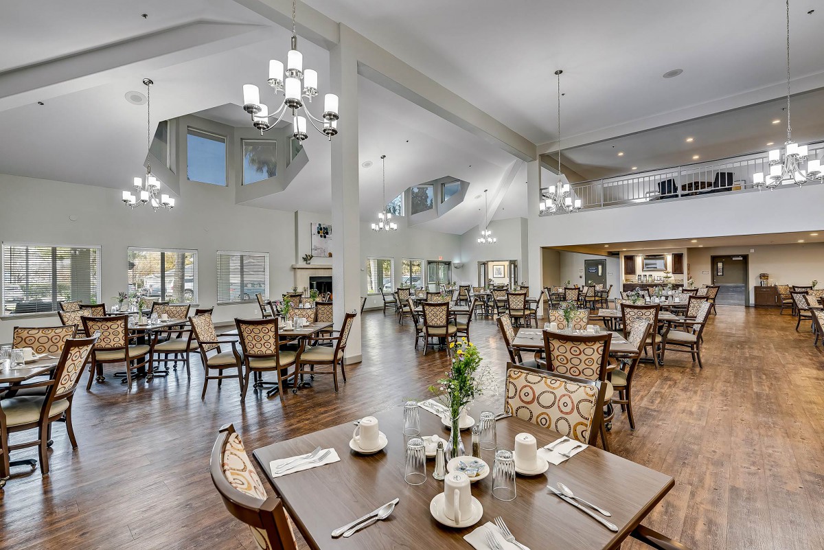 A spacious and elegantly decorated dining area with modern chandeliers and neatly arranged tables and chairs.