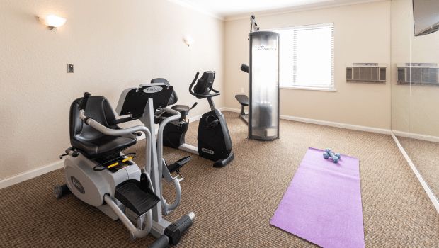 A small home gym setup with various exercise equipment including a treadmill, stationary bike, and yoga mat.