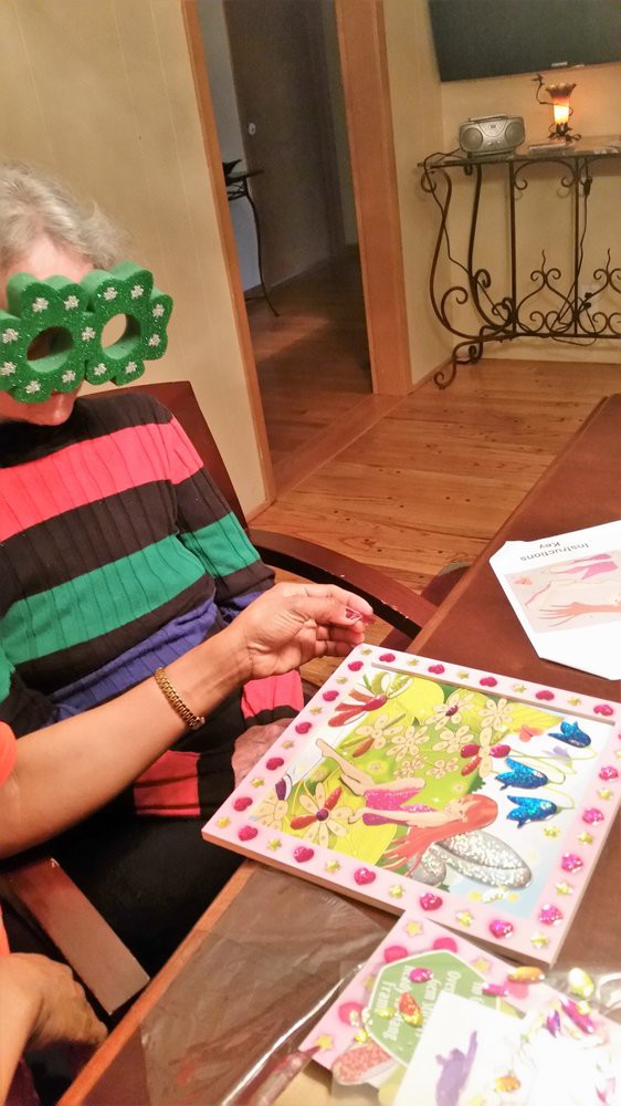 A person wearing novelty glasses engages in a colorful puzzle activity indoors.