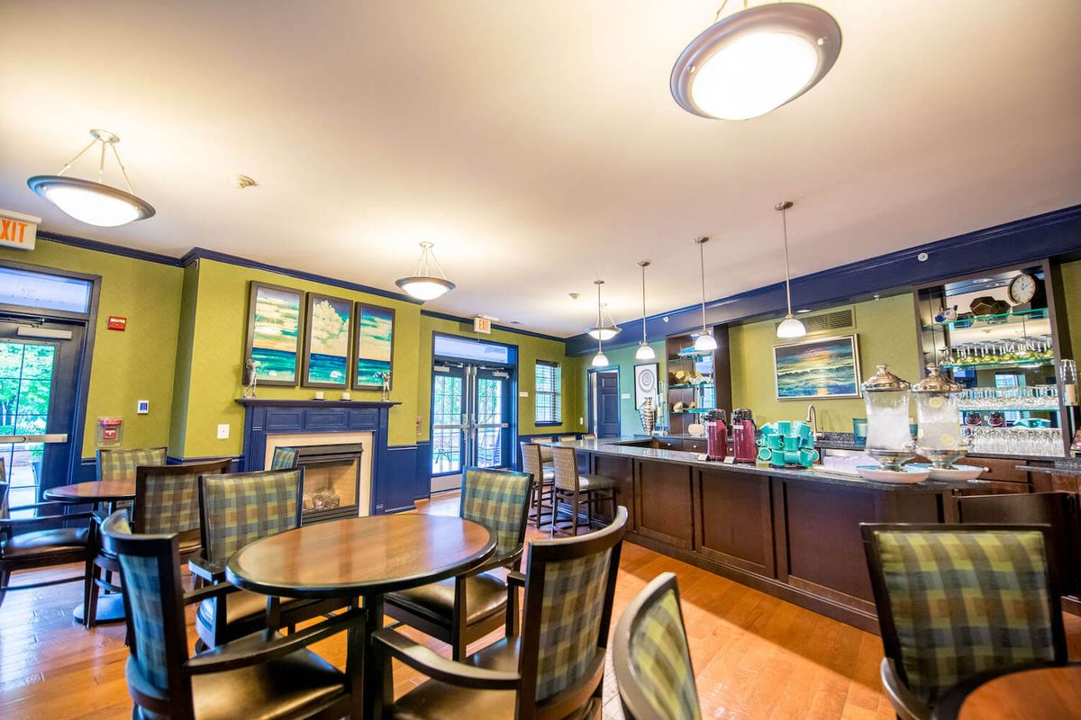 A cozy dining area featuring modern decor with tables and chairs, illuminated by overhead lighting.