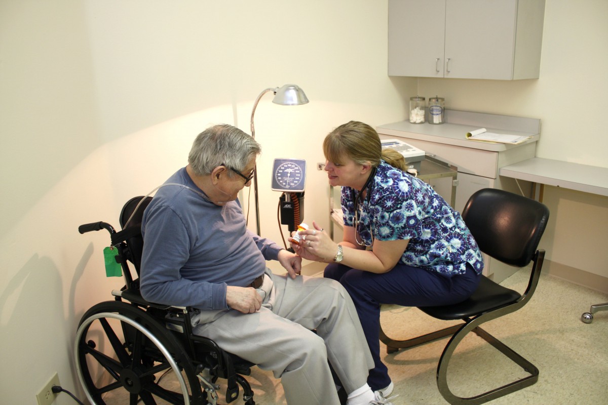 A healthcare professional consulting with a patient in a wheelchair at a medical clinic.