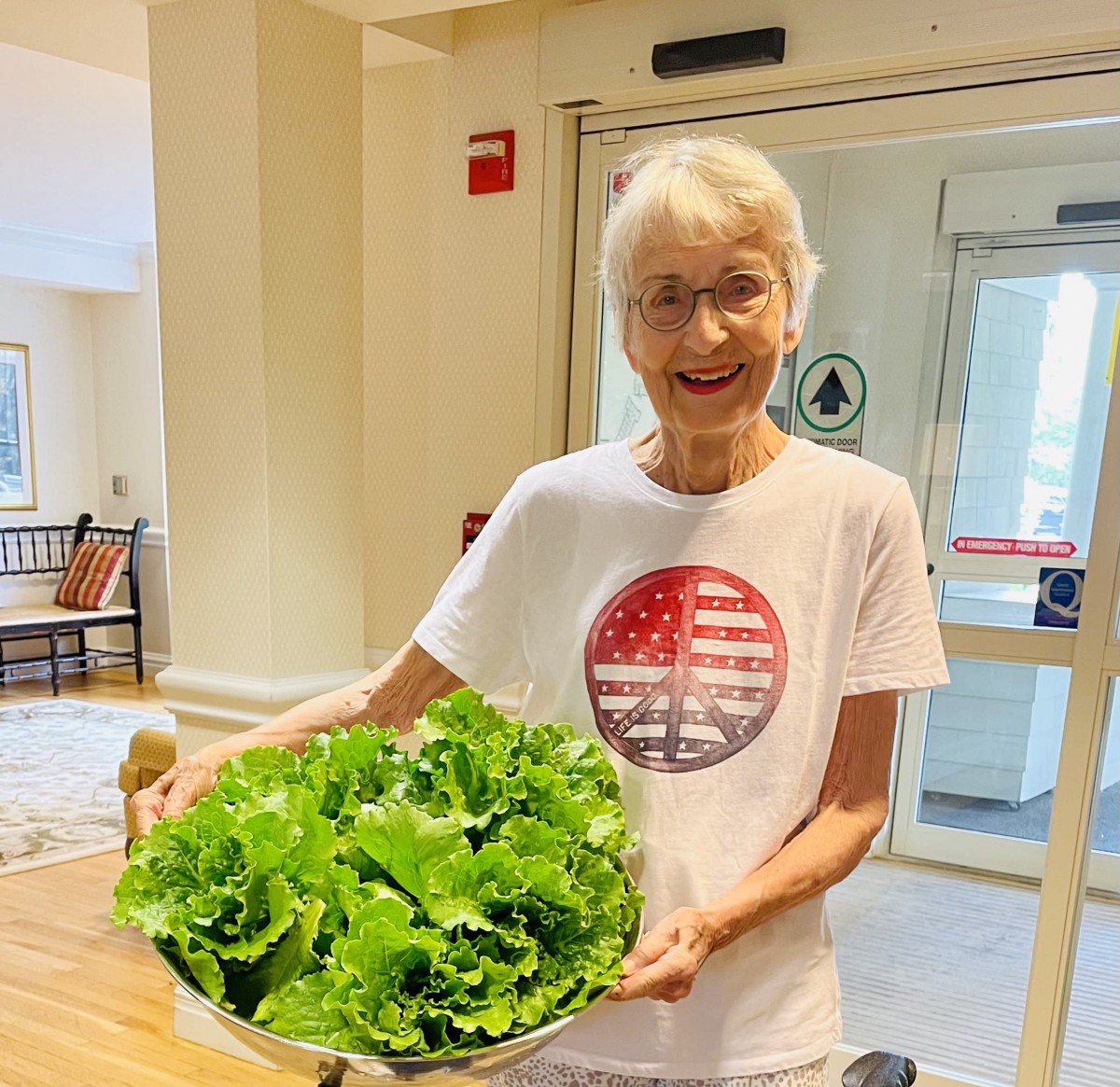 A person indoors holding a bowl of fresh lettuce.