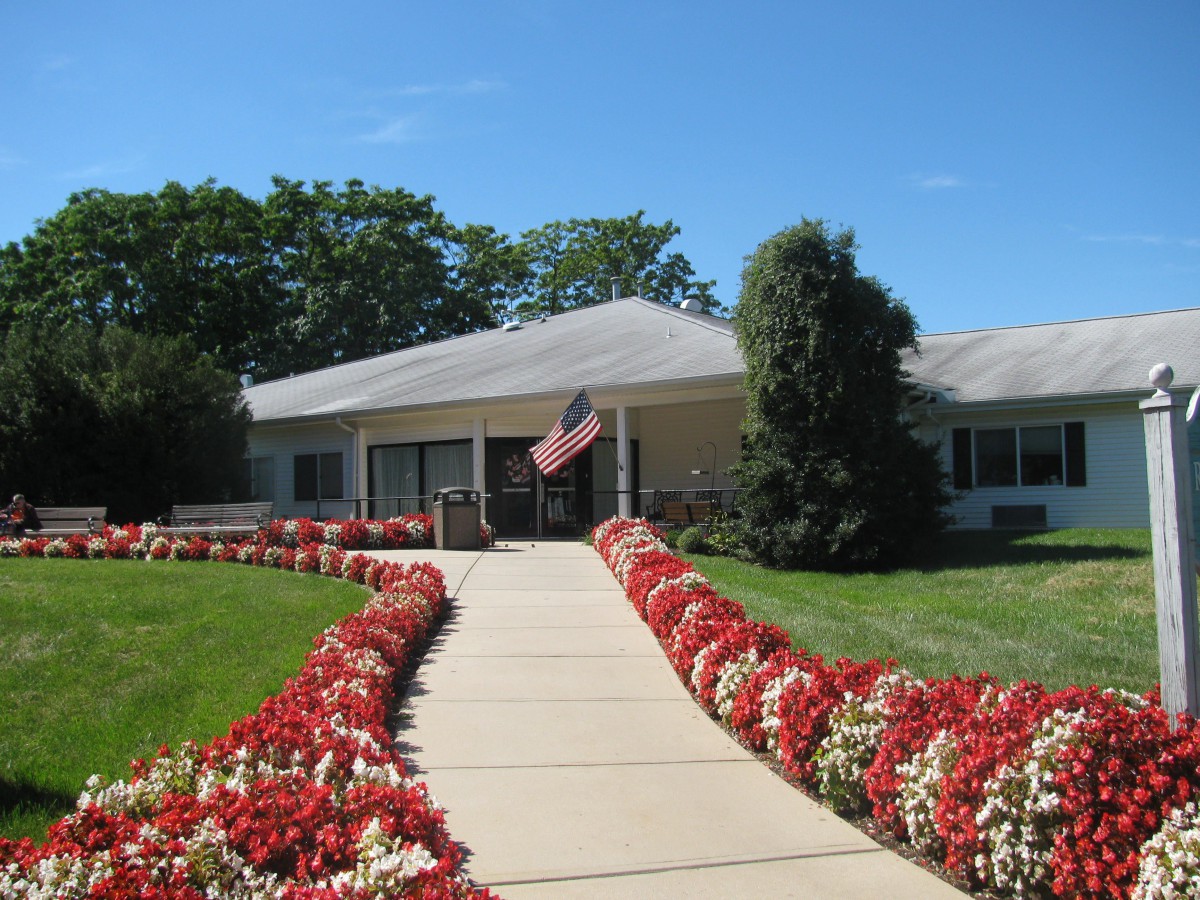 A well-maintained building with a pathway lined by colorful flowers and an American flag flying at the entrance.