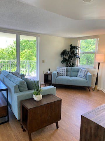 A cozy living room with modern furniture and a view of lush greenery through the large windows.