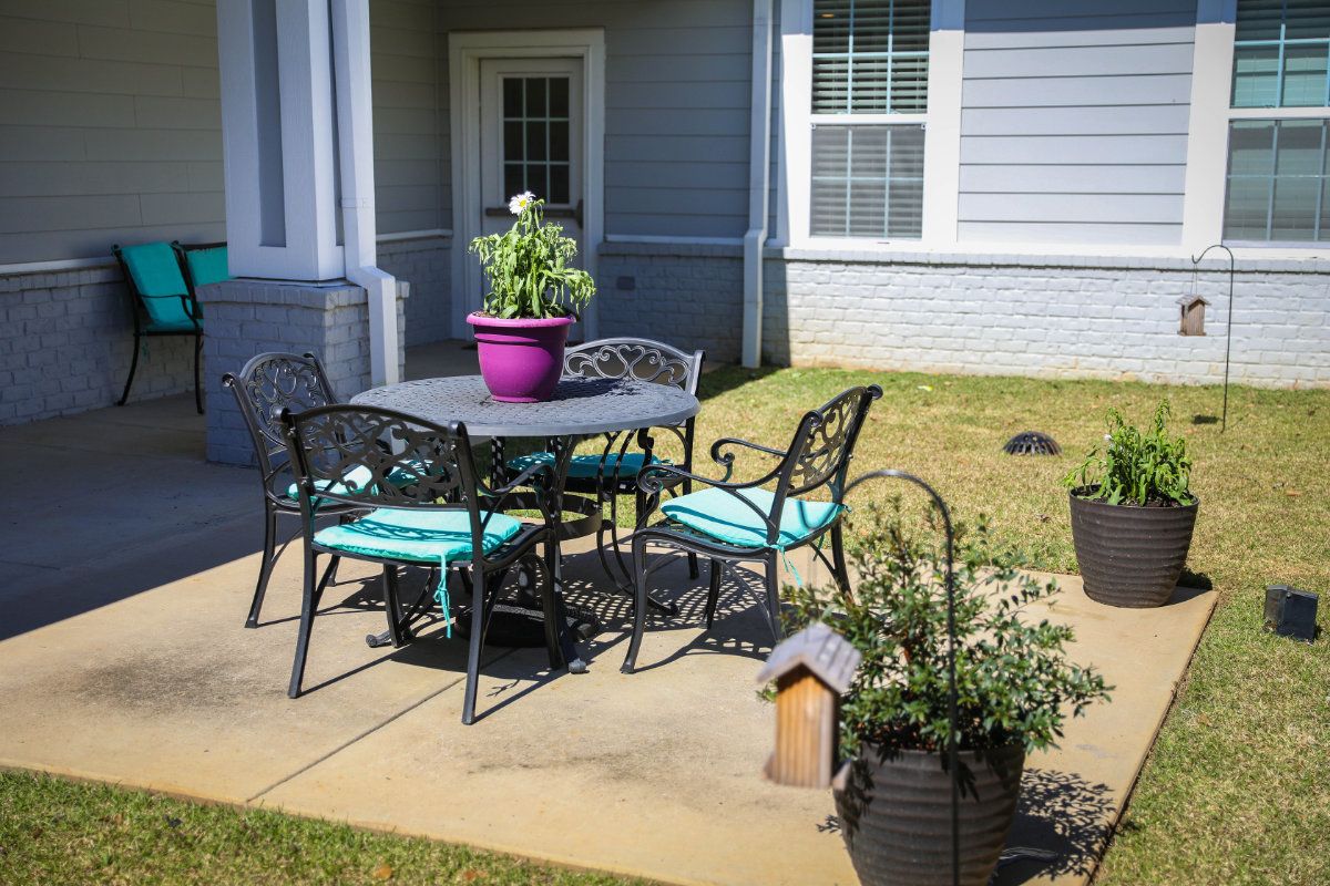 A cozy patio setup with a table and chairs, surrounded by potted plants in a backyard setting.