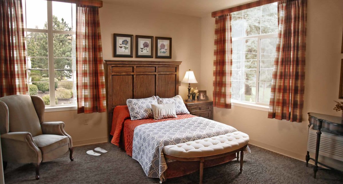 A cozy bedroom with patterned curtains, a neatly made bed, and warm lighting.