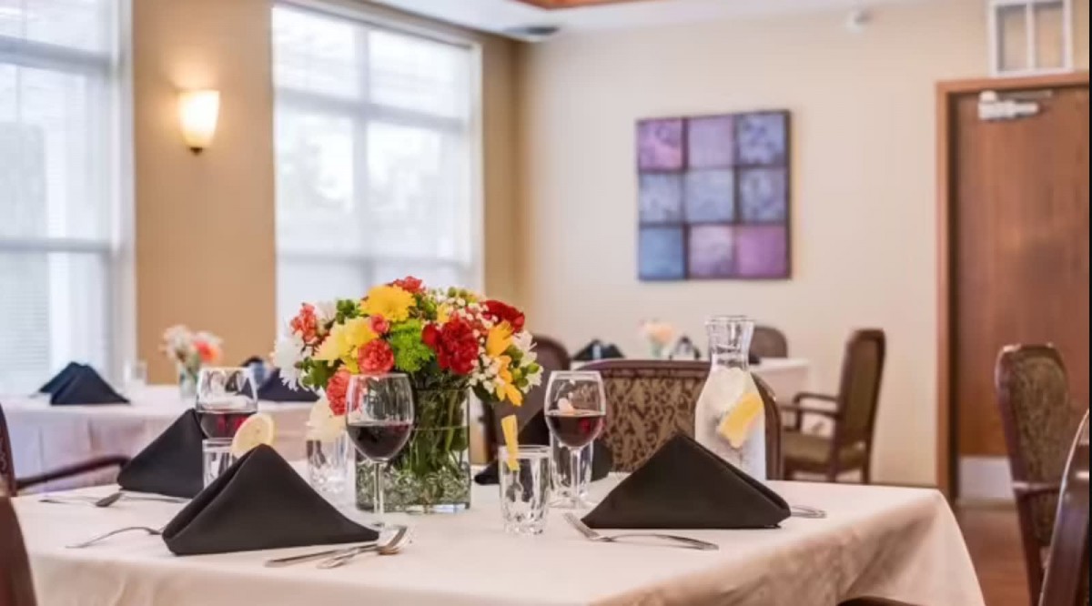 A beautifully set dining table with wine glasses and a colorful flower centerpiece in an elegant restaurant setting.