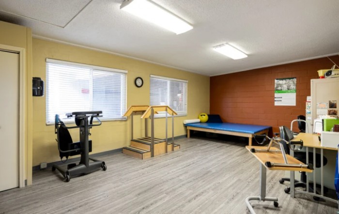 A physical therapy room equipped with a small staircase, exercise equipment, and a therapy bed.