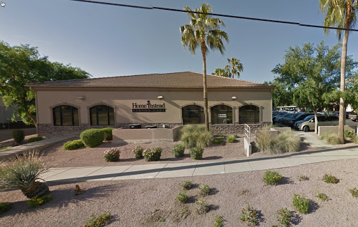 A commercial building featuring landscaping and palm trees.
