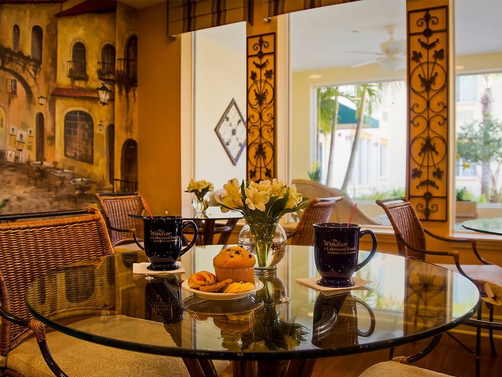 Cozy dining area with a glass table, adorned with flowers and coffee mugs.